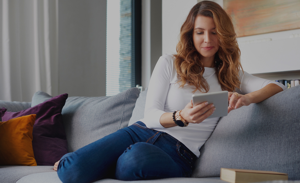 woman on sofa using notepad computer